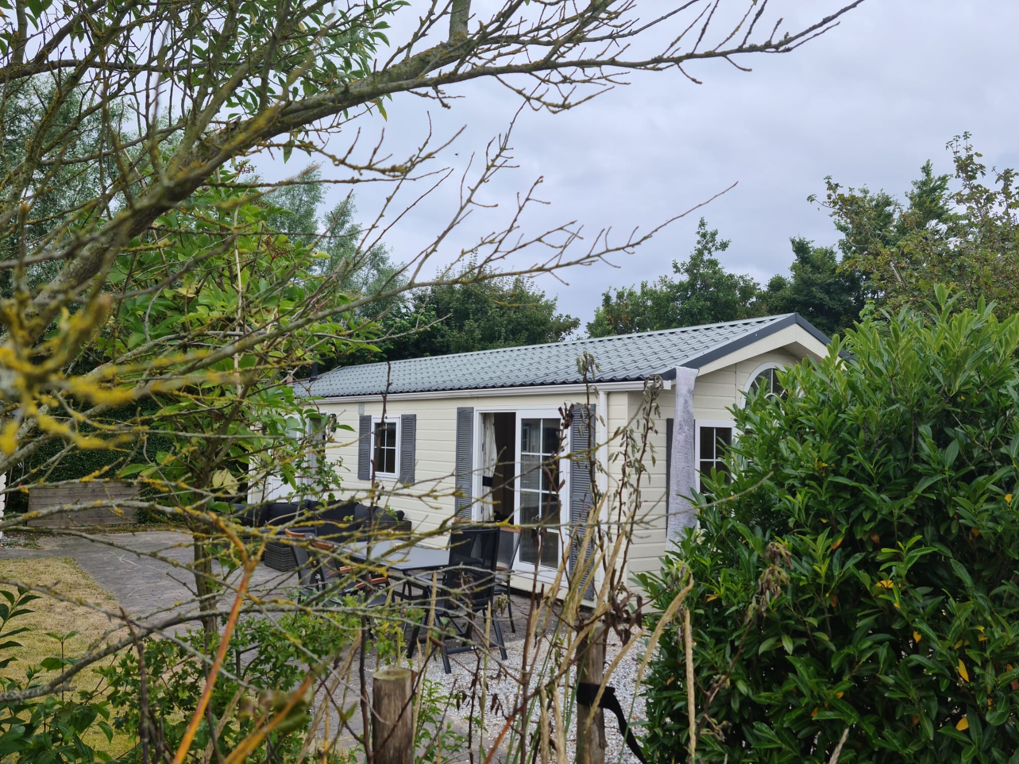 Foto van Chalet met bomen op de voorgrond.