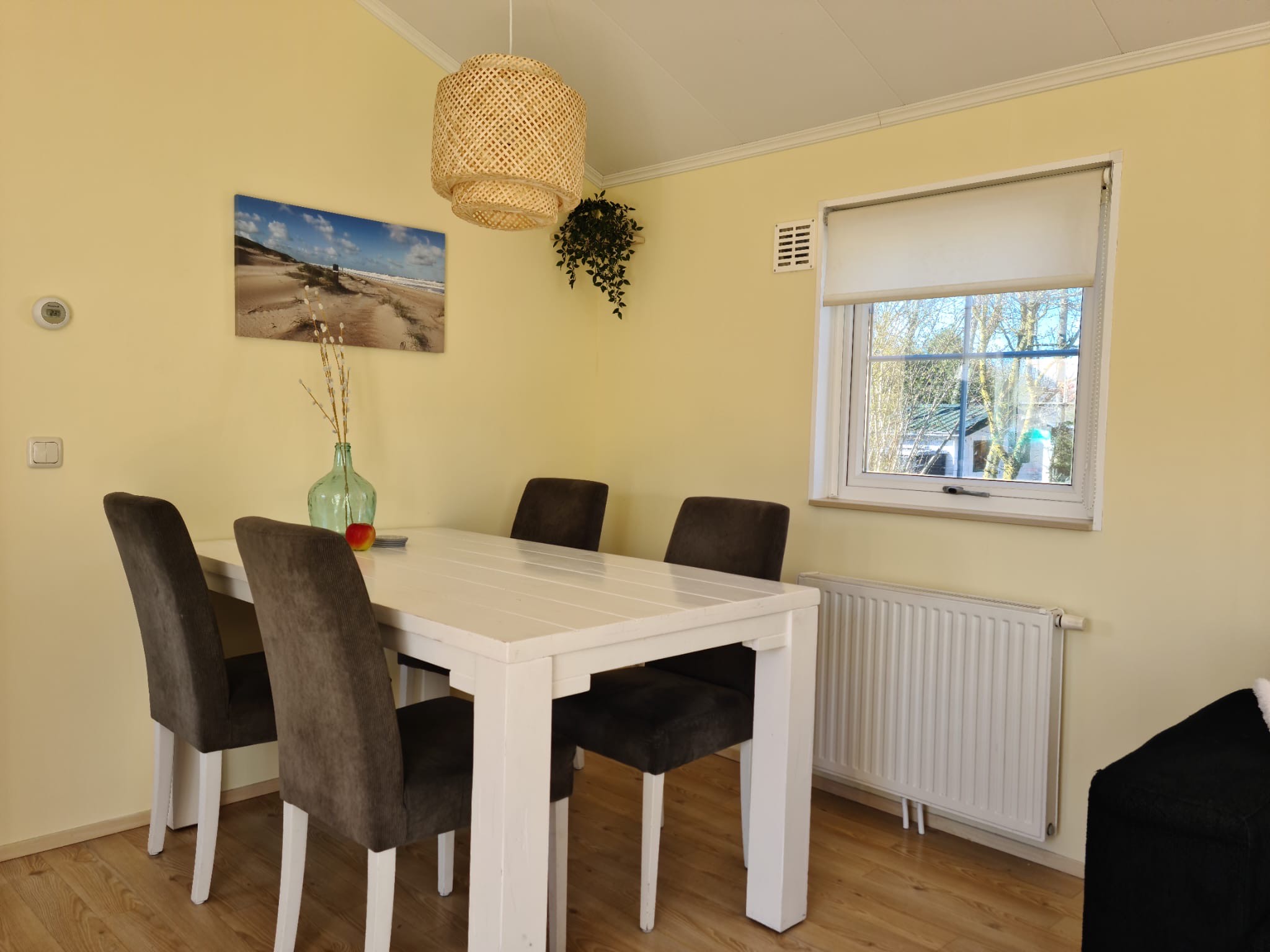 Woonkamer met aan de linkerkant een zwarte bank, in het midden een grijze tafel en aan de rechterkant een tv. 