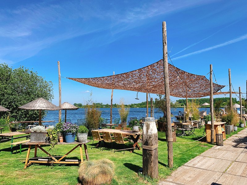 Restaurant met groot terras aan de rand van het Oostduinse meer op een zonnige dag.