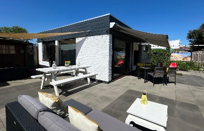 Ruime beschutte tuin met terras met meerdere zithoeken.