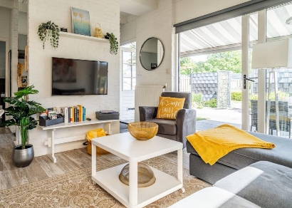 Foto van de woonkamer, bankstel met tv scherm aan de muur.