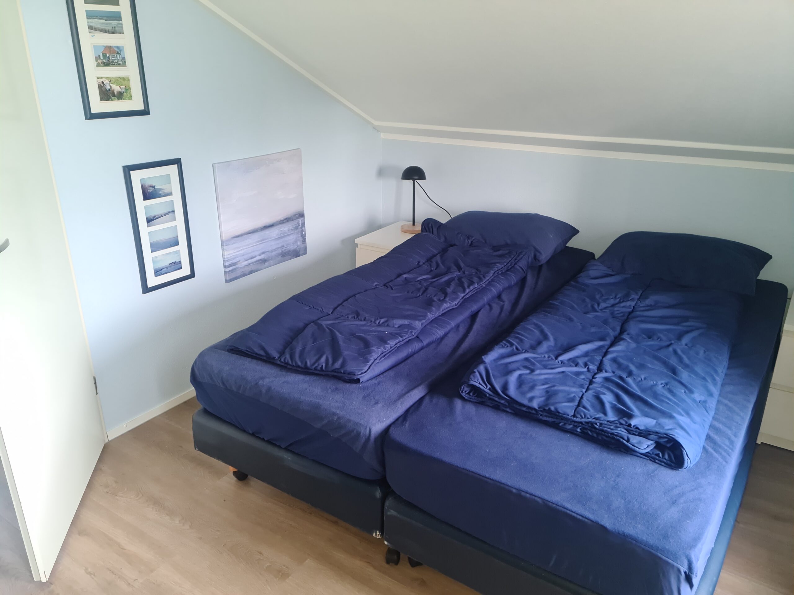 Slaapkamer boven aan de straatkant met twee losse eenpersoonsbedden en een grote houten kast.