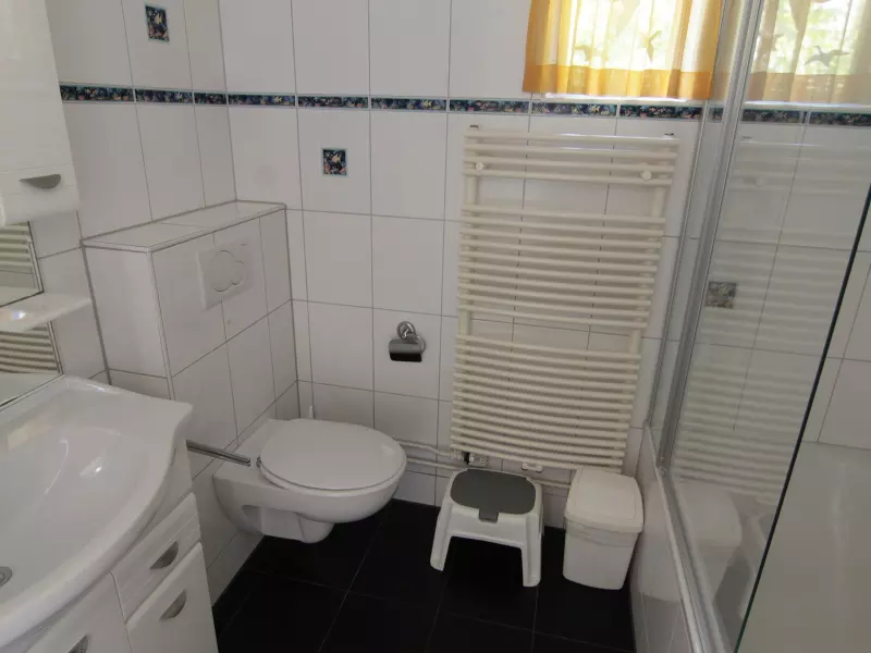 Badkamer beneden met wastafel met spiegel, toilet, ligbad met douche.