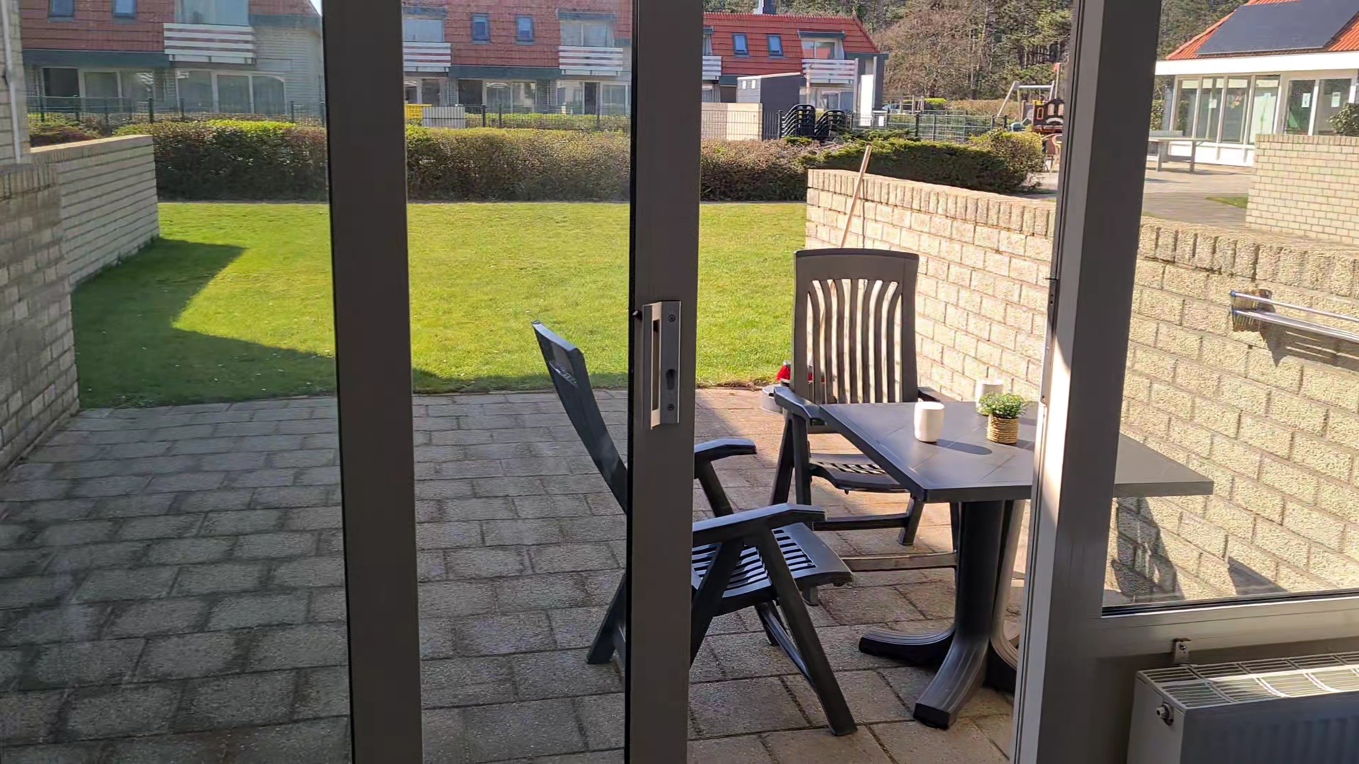 Woonkamer met aan de linkerkant een zwarte bank, in het midden een grijze tafel en aan de rechterkant een tv.