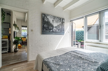 Kamer met tweepersoonsbed met kledingkast en openslaande deur naar de achterkant van de tuin.