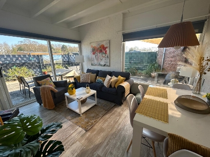 Gezellige woonkamer met zithoek, smart tv, eethoek, honden bed en schuifdeuren naar de tuin.