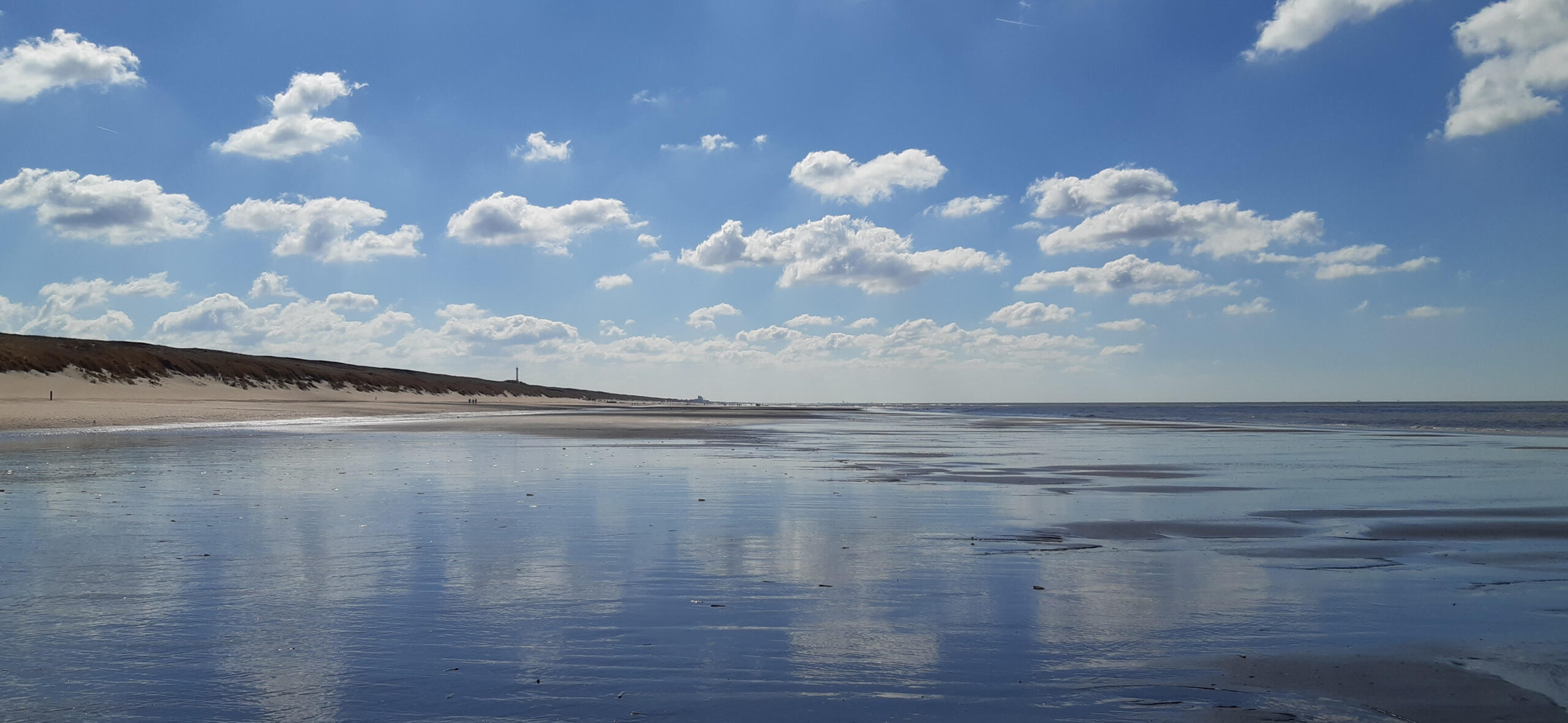 Foto van een leeg strand en zee met mix van blauwe lucht en wolken.