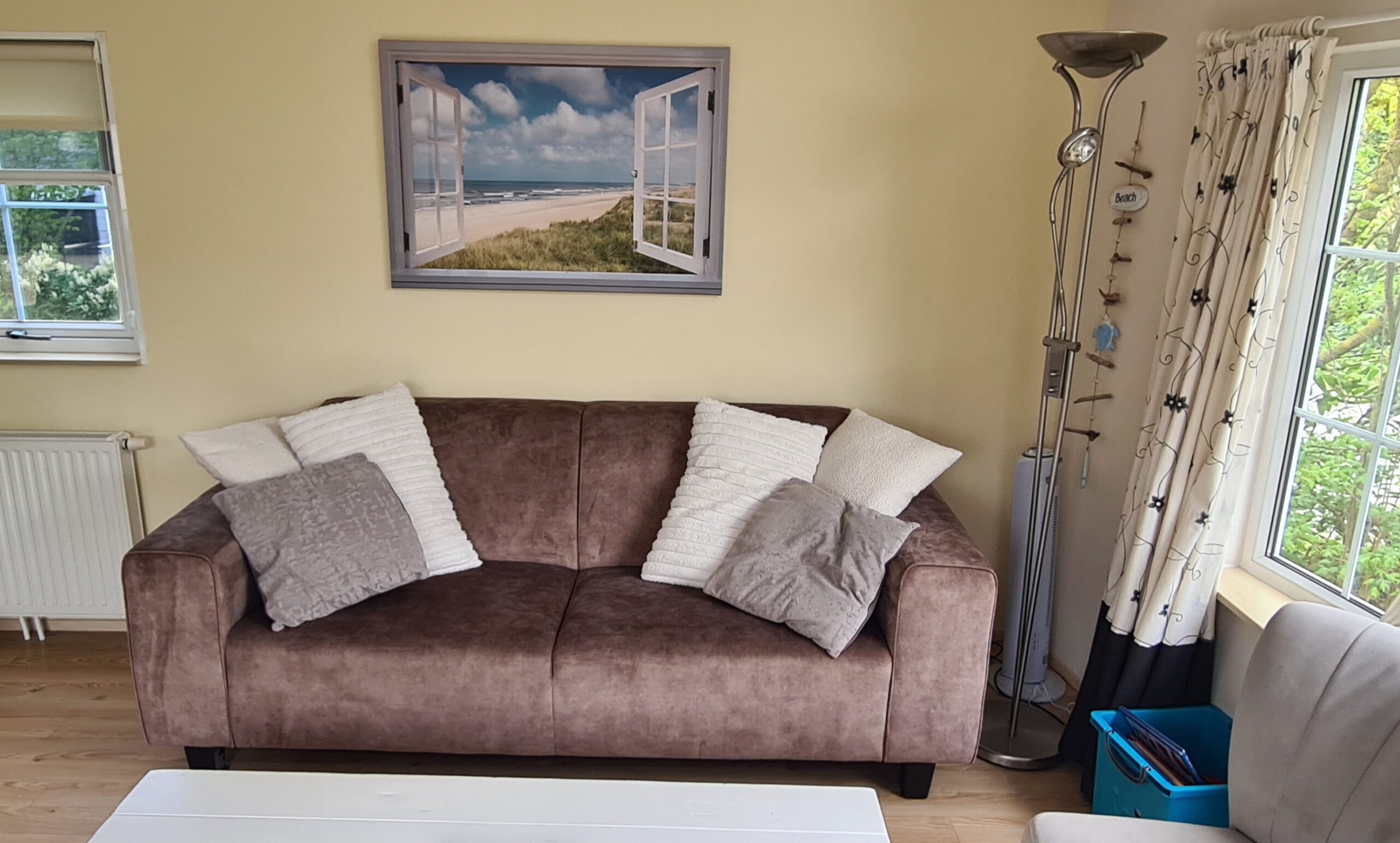 Woonkamer met aan de linkerkant een zwarte bank, in het midden een grijze tafel en aan de rechterkant een tv. 